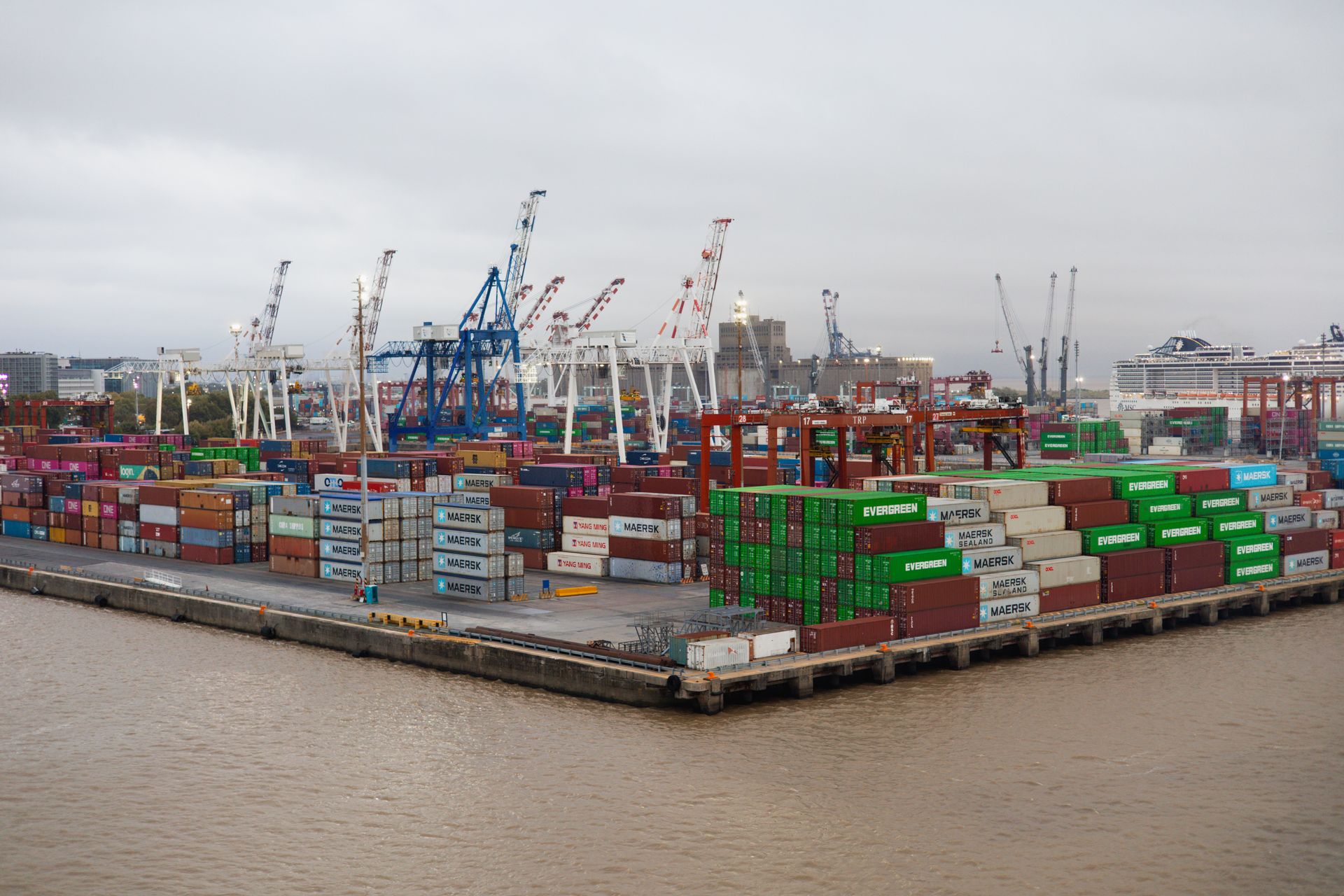 Terminal portuaire aux conteneurs empilés et aux grues de chargement sous un ciel couvert
